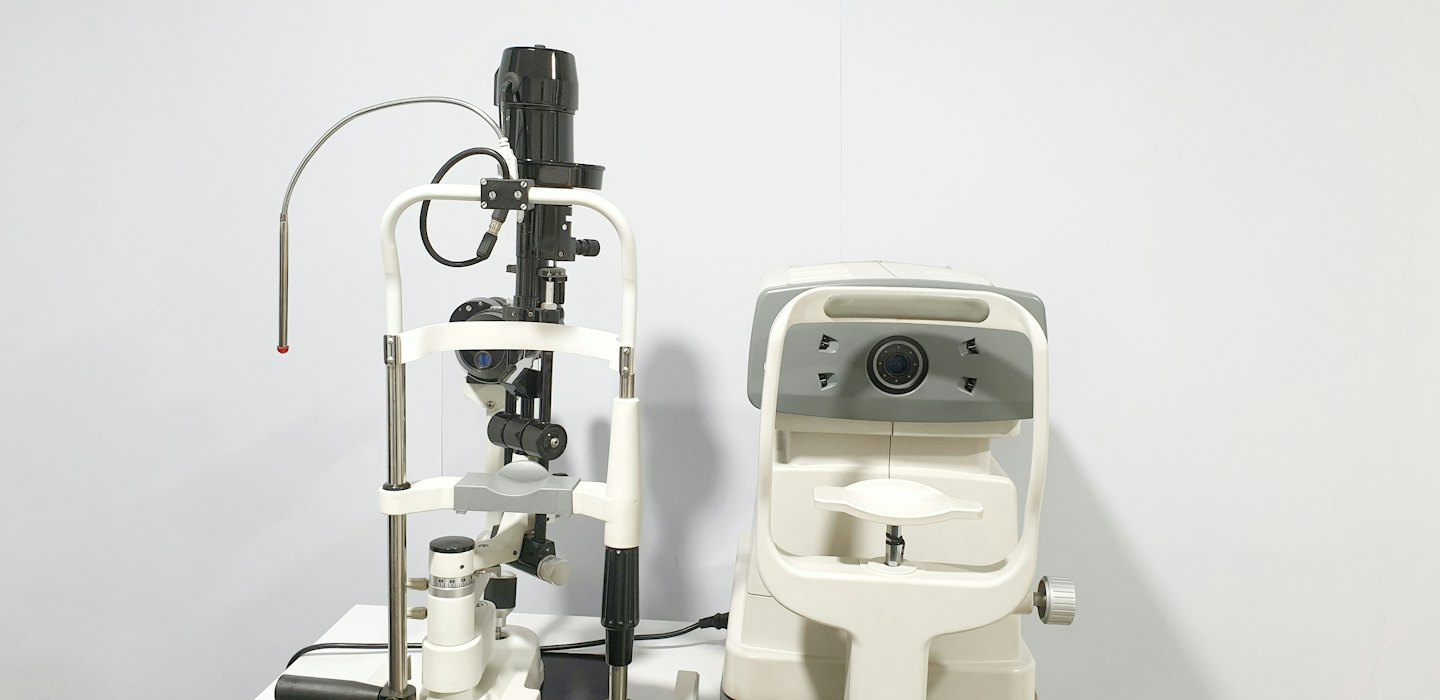 Ophthalmology slit lamp and auto-refractor on a white surface.