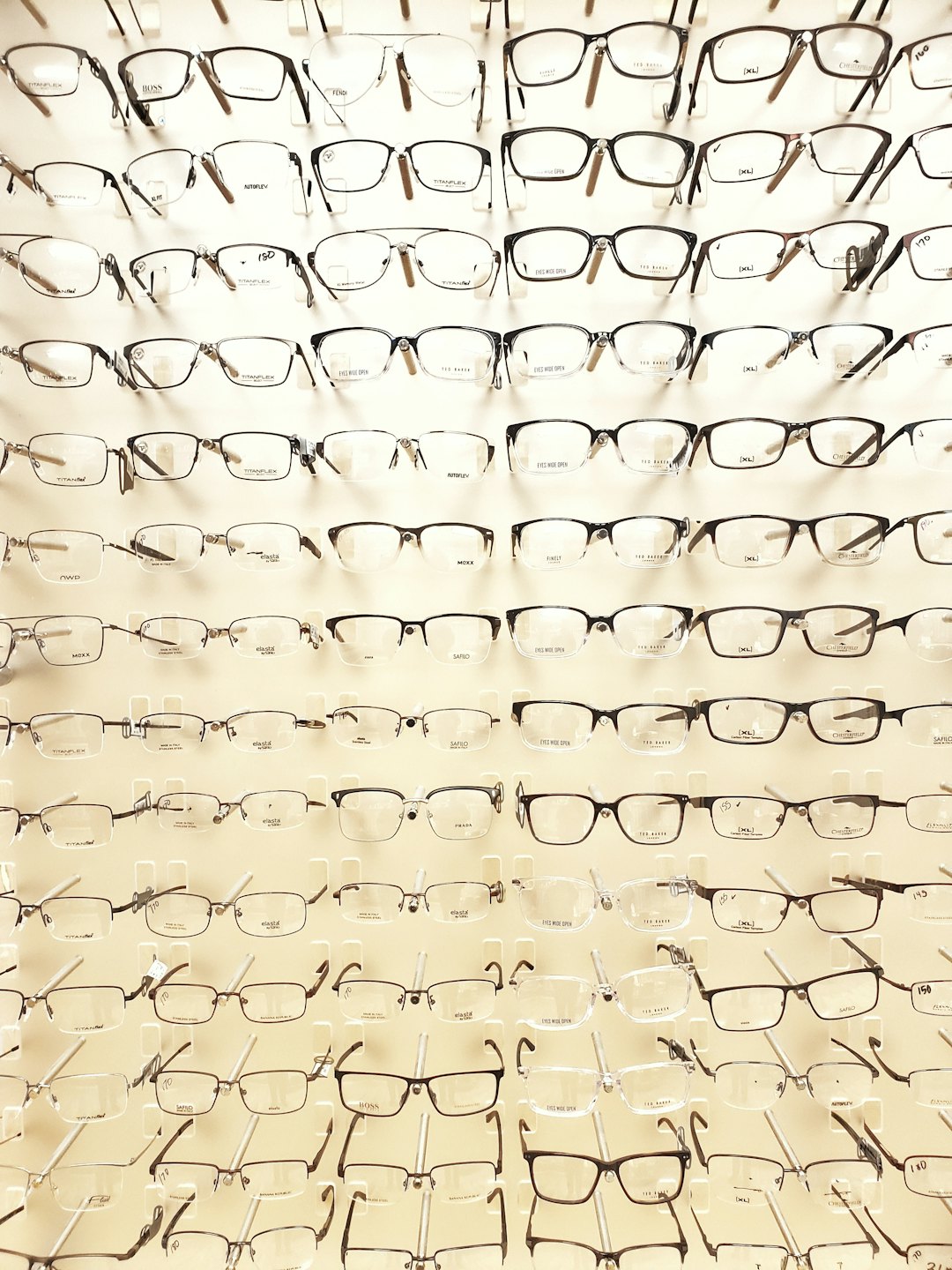 Various glasses frames displayed on a white wall in an optician.